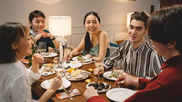 Friends share a meal around a table at a casual Friendsgiving dinner.