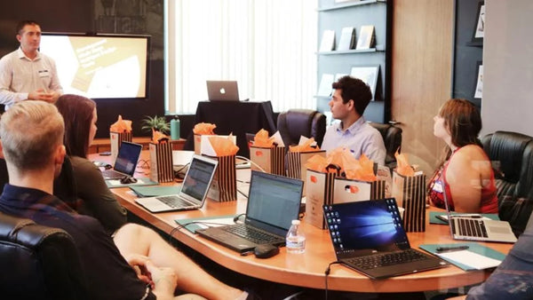 Team meeting in a conference room where laptops and note-taking devices capture an in-person discussion.
