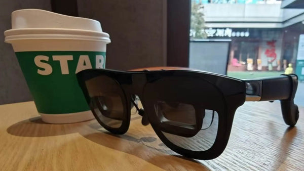 XREAL One Pro display glasses on a café table, showing the black frame and front optical modules.