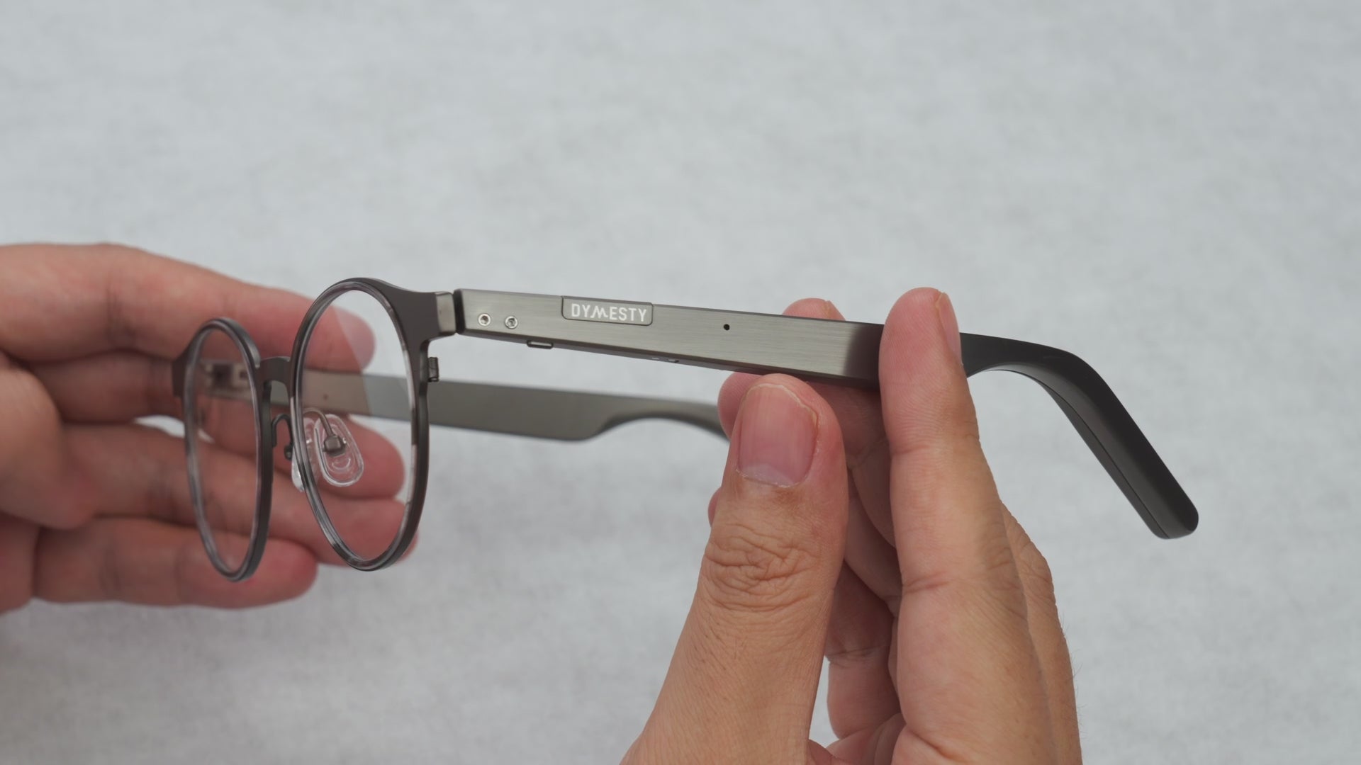 Hands holding Dymesty Jobs Circle round titanium AI glasses